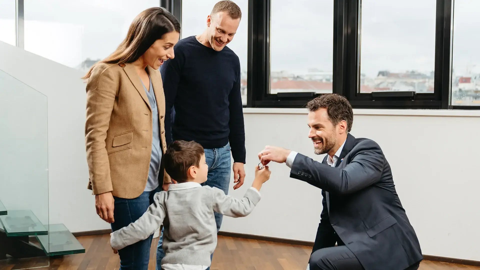 Agente immobiliare consegna le chiavi della nuova abitazione a una famiglia con bambino sorridente dopo l'acquisto della casa