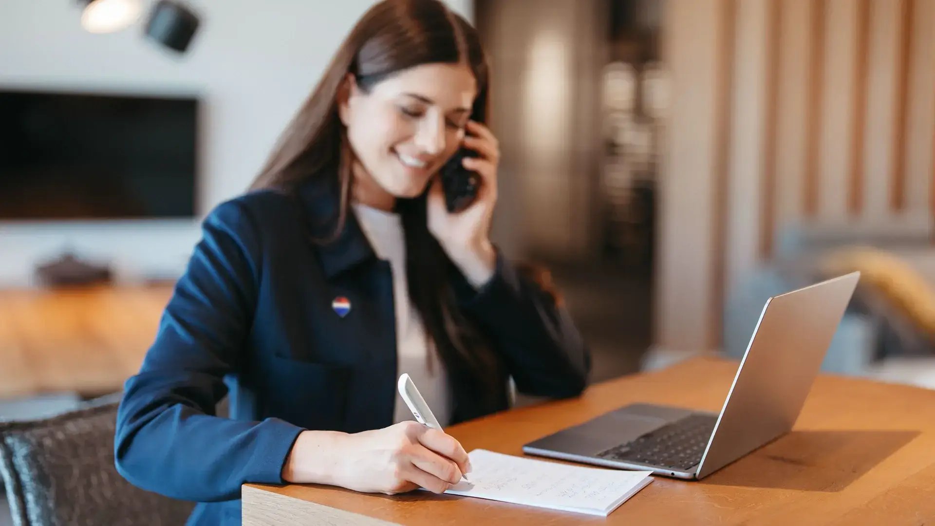 Consulente immobiliare REMAX sorridente al lavoro davanti al computer con la spilla del brand sulla giacca